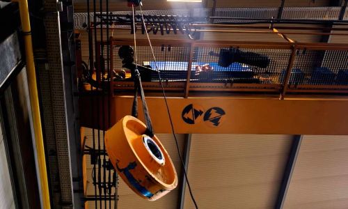 Schwerlastkran hebt große gelbe Last in Industriehalle, Tragkraftanzeige 38 Tonnen sichtbar am Träger.